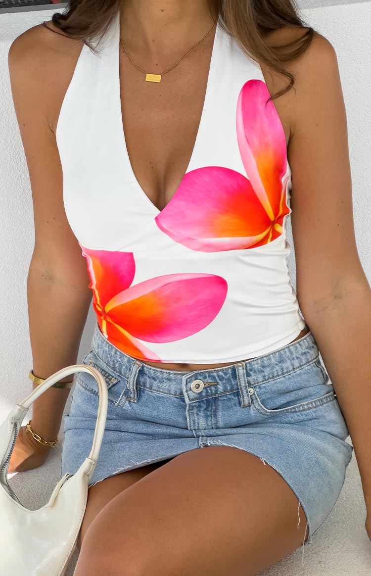 girl wearing a white halter neck top with frangipani print details